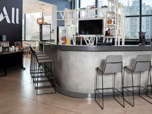 a bar with chairs and a counter with a tv at Novotel Sorocaba in Sorocaba