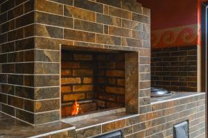 a brick fireplace with a fire in it at Kurjun Guest House in Bokonbayevo
