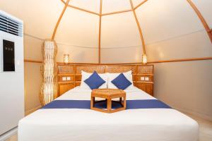 a bedroom with a bed with blue and white pillows at Triyana Resort and Glamping Carangsari Bali in Payangan