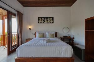a bedroom with a large white bed and a balcony at Kapouk Cottage in Nusa Penida