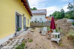 a backyard with a yellow house and an umbrella and chairs at Ferienwohnung Kleinramspau in Regenstauf
