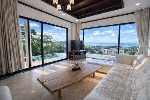a living room with a white couch and large windows at Skyline Seaview Villa-5 Bedroom, 4 Bathrooms with Private Seaview Pool in Ban Thong Phlu