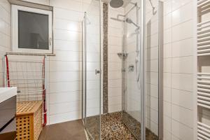 a glass shower in a bathroom with a tv at Ferienwohnung Kleinramspau in Regenstauf +19 photos