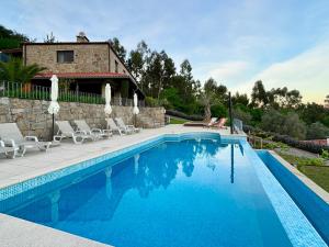 a swimming pool with chairs and a house at Casa Letrigo in Arcos de Valdevez