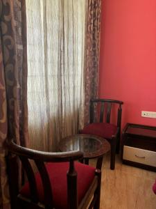 a room with two chairs and a table and a window at IMPERIAL COTTAGE, HILL BUNK OOTY in Ooty