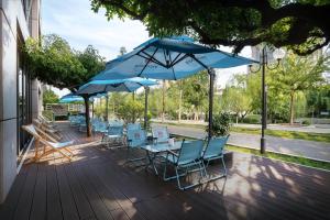 a deck with chairs and tables and umbrellas at Kempinski Hotel Beijing Yansha Center in Beijing