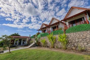a house with a stone wall and green grass at Kapouk Cottage in Nusa Penida