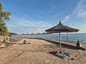 a group of people sitting on a beach with an umbrella at Glamour Pakoštane Mobile Home in Pakoštane