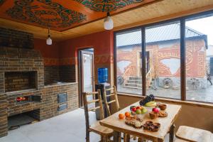 a dining room with a table and a fireplace at Kurjun Guest House in Bokonbayevo