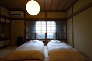 two beds in a room with a window at あかり by 4S STAY in Uchiko