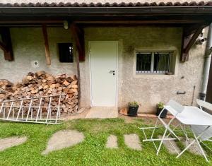 a house with a white door and a pile of logs at Le Studio nature de La Pra in Herbeys