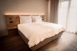 a bedroom with a large bed with white sheets and a window at Das Panorama Dependance in Caldaro