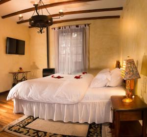 Un dormitorio con una cama blanca con flores rojas. en Hostería La Andaluza en Riobamba