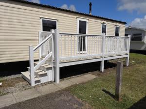 a white deck with a staircase next to a house at Magnolia in Porthcawl