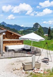 a patio with an umbrella and a couch and a chair at Almhütte Bairau Kaser in Lofer