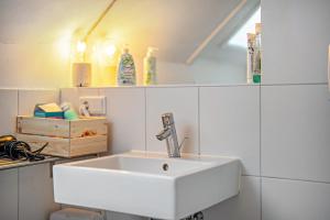 a white sink in a white tiled bathroom at Large Apartment 60 M² With Garden in Emmendingen +23 photos