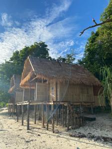 a house with a straw roof on the beach at Kainora Homestay in Dayang
