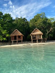 two huts on a tropical island in the water at Kainora Homestay in Dayang