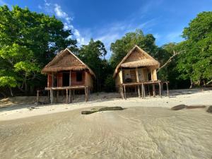 two huts on a beach with a snake in the sand at Kainora Homestay in Dayang