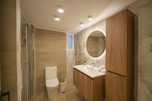 a bathroom with a sink and a toilet and a mirror at Corali 1 - Coastal Retreat in Katakolo