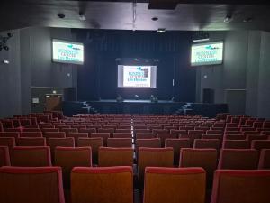 an empty auditorium with red chairs and two screens at Village Club Les Hyvans in Chorges +65 photos