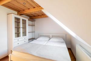 a bedroom with a white bed and a staircase at Kralova Apartment in Modra in Modra