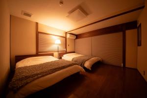 a bedroom with two beds and a lamp in it at GENPEI Guest House in Takamatsu
