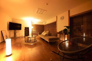 a living room with a couch and a tv at GENPEI Guest House in Takamatsu