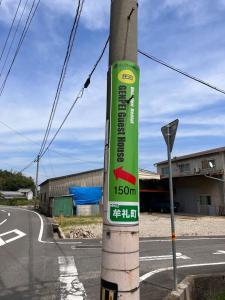 a green sign on a pole on a street at GENPEI Guest House in Takamatsu