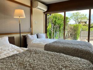 two beds in a room with a large window at GENPEI Guest House in Takamatsu +31 photos