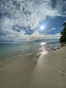 a view of a beach with the sun and the ocean at Kainora Homestay in Dayang