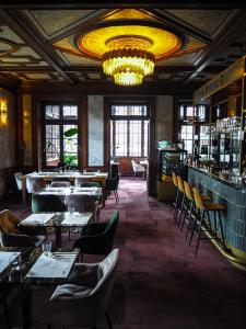 a restaurant with tables and chairs and a chandelier at Hotel i Restauracja Pałacyk Tyrolski in Żyrardów