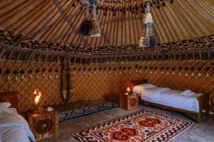 a room with two beds and a rug in a yurt at Kurjun Guest House in Bokonbayevo