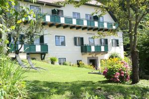 a large white building with green balconies and a yard at Petersenhof in Millstatt