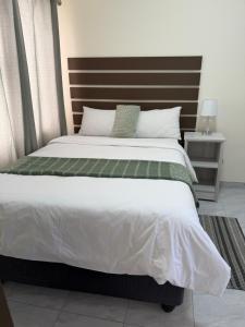 a bedroom with a large bed with a wooden headboard at Coastwave Guesthouse CBD in Walvis Bay
