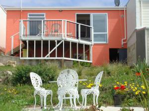 two chairs and a table in front of a house at Oamaru Pink Cottage in Oamaru