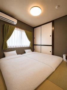 a bedroom with two beds and a window at WinGoodDays in Kumamoto