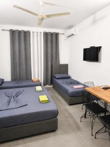 a room with two beds and a table and a tv at Klea Rooms in Velipojë