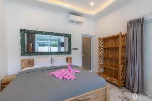 a bedroom with a large bed with a pink dress on it at Made's Dream Villa Amed in Amed