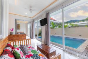 a living room with a couch and a tv and a pool at Made's Dream Villa Amed in Amed