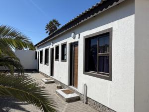 a white house with windows and a palm tree at Coastwave Guesthouse CBD in Walvis Bay
