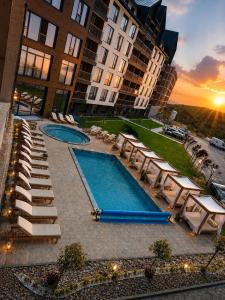 a hotel with a pool and chairs and a building at Deluxe Mountain View Studio ViS in Residence Hill Hotel Kopaonik in Kopaonik