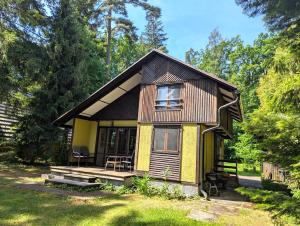 a small yellow house with a porch in a yard at Chata Oliva in Planá nad Lužnicí