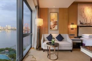 a hotel room with a couch and a bed and a window at Hilton Wuhan Yangtze Riverside in Wuhan
