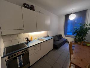 a kitchen with white cabinets and a couch in a room at Flat 12-min walk to Bern station in Bern