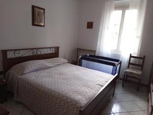 a bedroom with a bed and a chair and a window at Appartamento Rosa in Savio di Ravenna