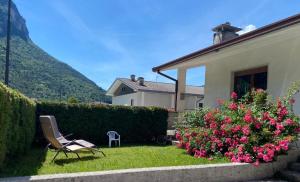 a chair in the yard of a house with flowers at Casa Lalli in Longarone