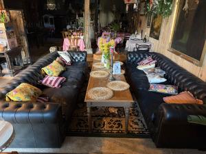 a living room with black leather couches and a table at L Annexe d Aubrac in Aubrac +36 photos