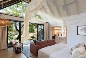 a bedroom with a bed and a couch and a large window at Lion Sands River Lodge in Sabi Sand Game Reserve +35 photos