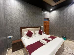 a bedroom with a large white bed with red pillows at Hotel Shreeji Palace - OPP Hanuman Garhi Mandir in Ayodhya